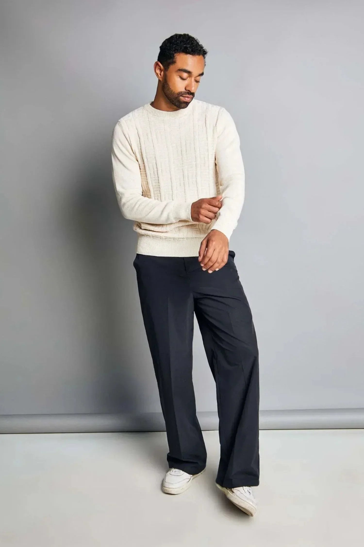 Hombre con suéter de punto beige y pantalón negro, moda casual para hombre